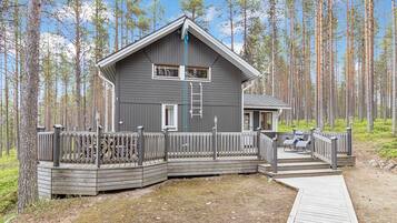 Mökki, jossa on terassi, ja jonka ympärillä on metsää.
