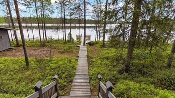 A wooden boardwalk leading to a dock with a boat, surrounded by dense greenery and trees.