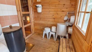 A wooden interior with a wooden bench, a trash can, and a window.