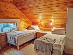 Een gezellig vakantiehuisje met twee bedden, een klein tafeltje en een raam.