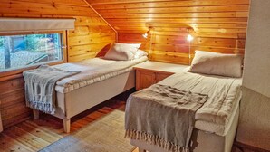 Ein gemütliches Blockhauszimmer mit zwei Betten, Holzwänden, einem Fenster und einem kleinen Tisch.