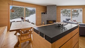 Una cucina moderna con mobili in legno, un'isola centrale e ampie finestre che offrono vista su un paesaggio innevato.