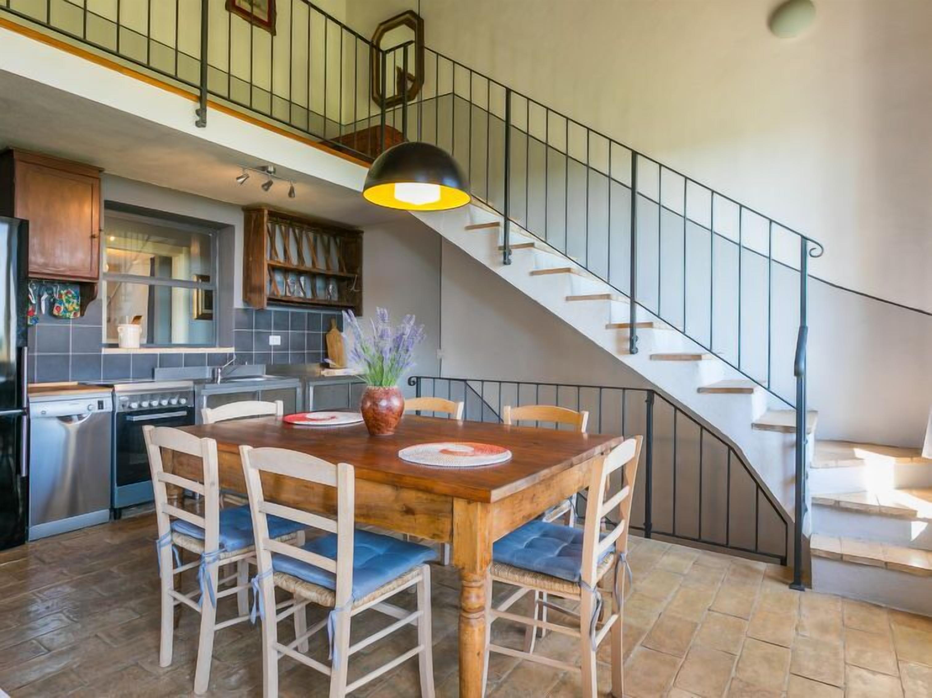 A spacious kitchen with a dining area, a staircase, and a view of the upper floor.