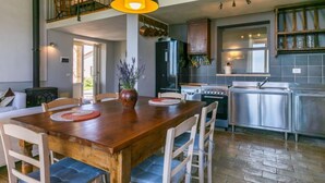 A spacious kitchen with a wooden dining table, modern appliances, and a view of the upper floor.