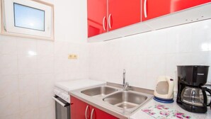 A kitchen with red cabinets, a double sink, a coffee maker, and a toaster. - Apartment Vinka by Interhome (Trogir)