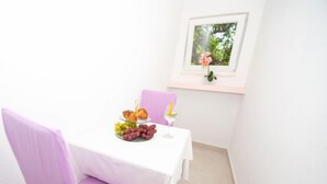 A small dining area with a table set for two, featuring a plate of grapes, a croissant, and a glass of wine. - Apartment Vinka by Interhome (Trogir)