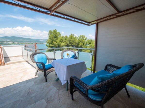 Un espacio de estar al aire libre cubierto con mobiliario de mimbre y una mesa, con vistas a un paisaje pintoresco.