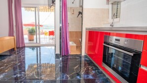 Une cuisine moderne aux couleurs rouge et blanche, dotée d’un grand four et offrant une vue sur un espace extérieur aménagé pour se détendre.