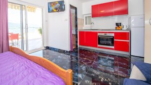 Une cuisine moderne avec des meubles de rangement rouges, un four encastré et un réfrigérateur.