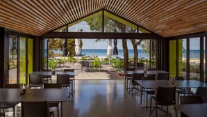 Comedor interior moderno con vistas a la playa, con techos de listones de madera y paredes de vidrio.