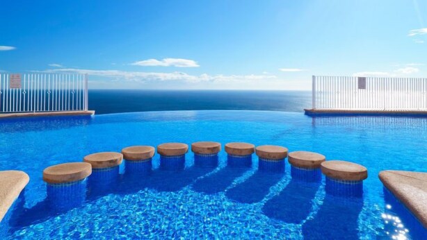 Ein Infinity-Pool mit freiem Blick auf den Ozean und strahlender Sonne.