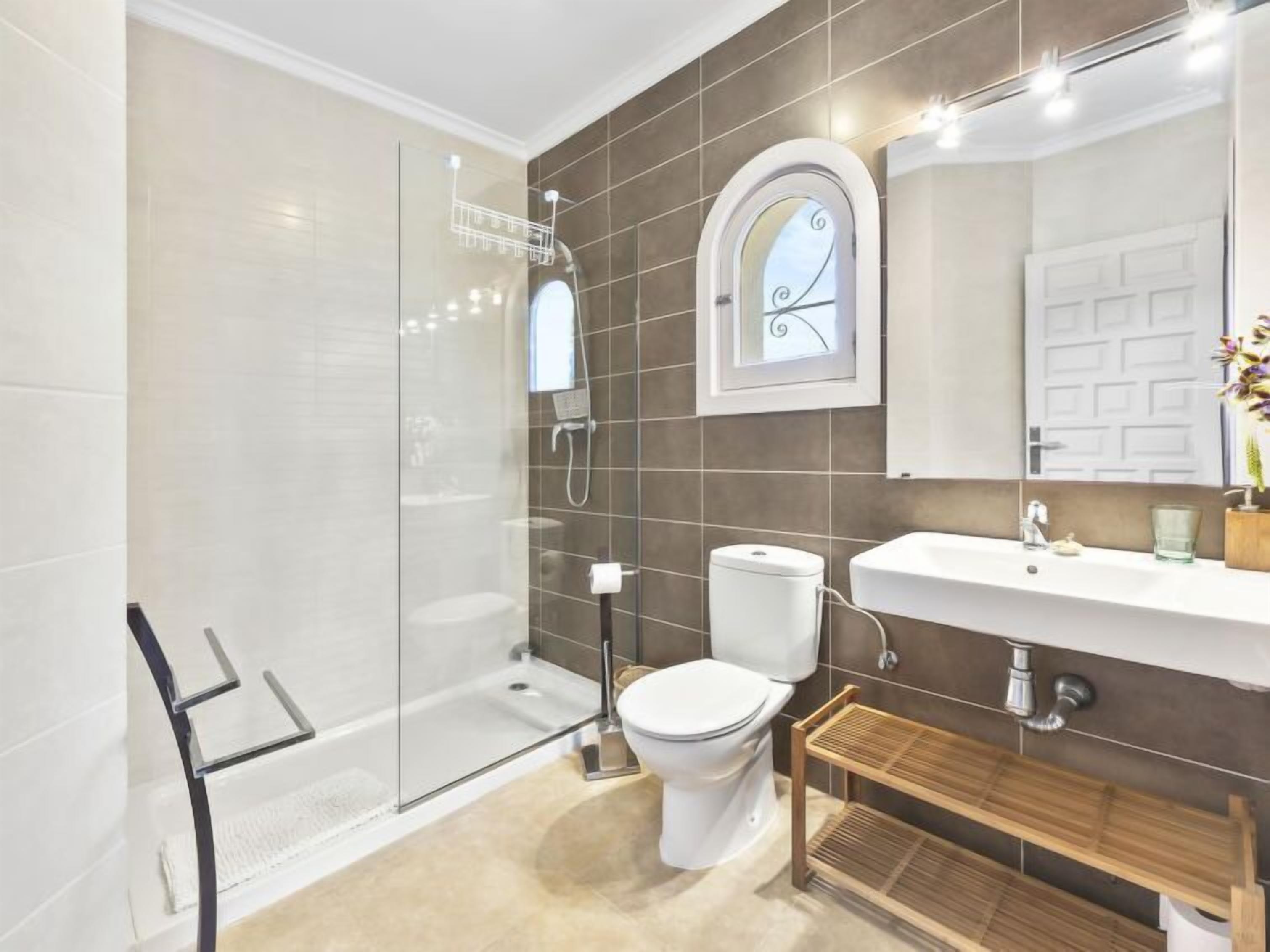 A modern bathroom with a glass shower enclosure, a toilet, a sink, and a vanity.