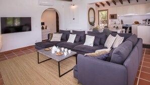 Un salon moderne avec un canapé d’angle gris, une table basse et un téléviseur fixé au mur.