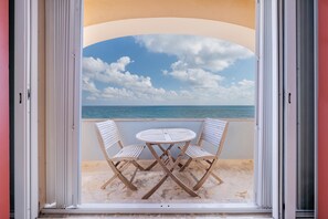 A balcony with a table and chairs, overlooking a beach and the sea. - Caribbean Views. 2 BR at Isla 33. Rooftop Pool. (Isla Mujeres)
