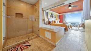 A spacious bathroom with a glass-enclosed shower, a bathtub, and a sunlit room with a balcony. - Caribbean Views. 2 BR at Isla 33. Rooftop Pool. (Isla Mujeres)