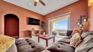 A living room with a sofa, a coffee table, a TV, and a plant. - Caribbean Views. 2 BR at Isla 33. Rooftop Pool. (Isla Mujeres)