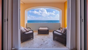 An open balcony with wicker furniture and a view of the sea. - Caribbean Views. 2 BR at Isla 33. Rooftop Pool. (Isla Mujeres)
