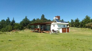 A house with a large deck, a motorcycle parked in front, and a clear view of the surrounding forest. - Kleines Landhaus in 25 Ha in den Bergen von Córdoba, im Herz Argentiniens (Villa Berna)