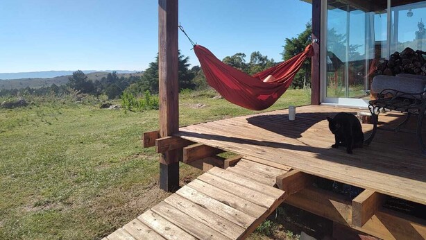 A wooden deck with a hammock, a bench, and a cat. - Kleines Landhaus in 25 Ha in den Bergen von Córdoba, im Herz Argentiniens (Villa Berna)