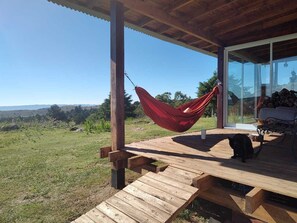 Eine Holzterrasse mit einer Hängematte, einer Bank und einer Katze.