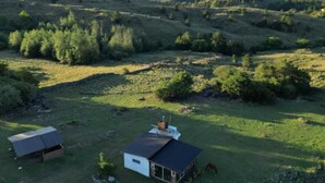 A rural landscape with two small buildings, one with a dark roof and another with a white roof, surrounded by greenery and hills in the background. - Kleines Landhaus in 25 Ha in den Bergen von Córdoba, im Herz Argentiniens (Villa Berna)