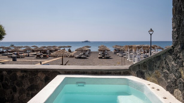 A pool area with a view of the beach and ocean. - Sand Gem - Beach Apartments (Santorini)