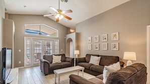 Ein geräumiges Wohnzimmer mit zwei braunen Sofas, einem weißen Couchtisch und einem Deckenventilator.