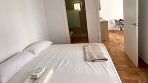 A hotel room with a large bed, a small table, and a chair. There is a door leading to a bathroom and a balcony. - Casa en El Palmar de Vejer a 200 Metros de la Playa (El Palmar de Vejer)