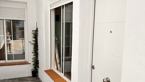 A clean, modern exterior with a white door, a window with a wooden bench, and a potted plant. - Casa en El Palmar de Vejer a 200 Metros de la Playa (El Palmar de Vejer)