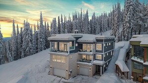 Un chalet à plusieurs étages doté d’un balcon, entouré d’arbres couverts de neige et situé à proximité d’une piste de ski.