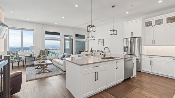 Une cuisine moderne avec des meubles blancs, des appareils en acier inoxydable et des luminaires suspendus.