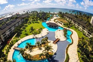Un resort con múltiples piscinas, una zona de playa y vistas al océano.