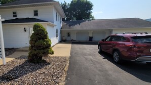 Ein zweistöckiges Haus mit Garage, ein roter Geländewagen auf der Auffahrt und ein kleiner Baum im Vorgarten.