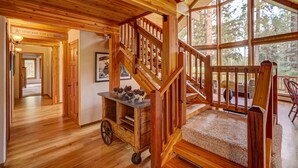 Interior de madera con una escalera, un carrito decorado y vistas al exterior.