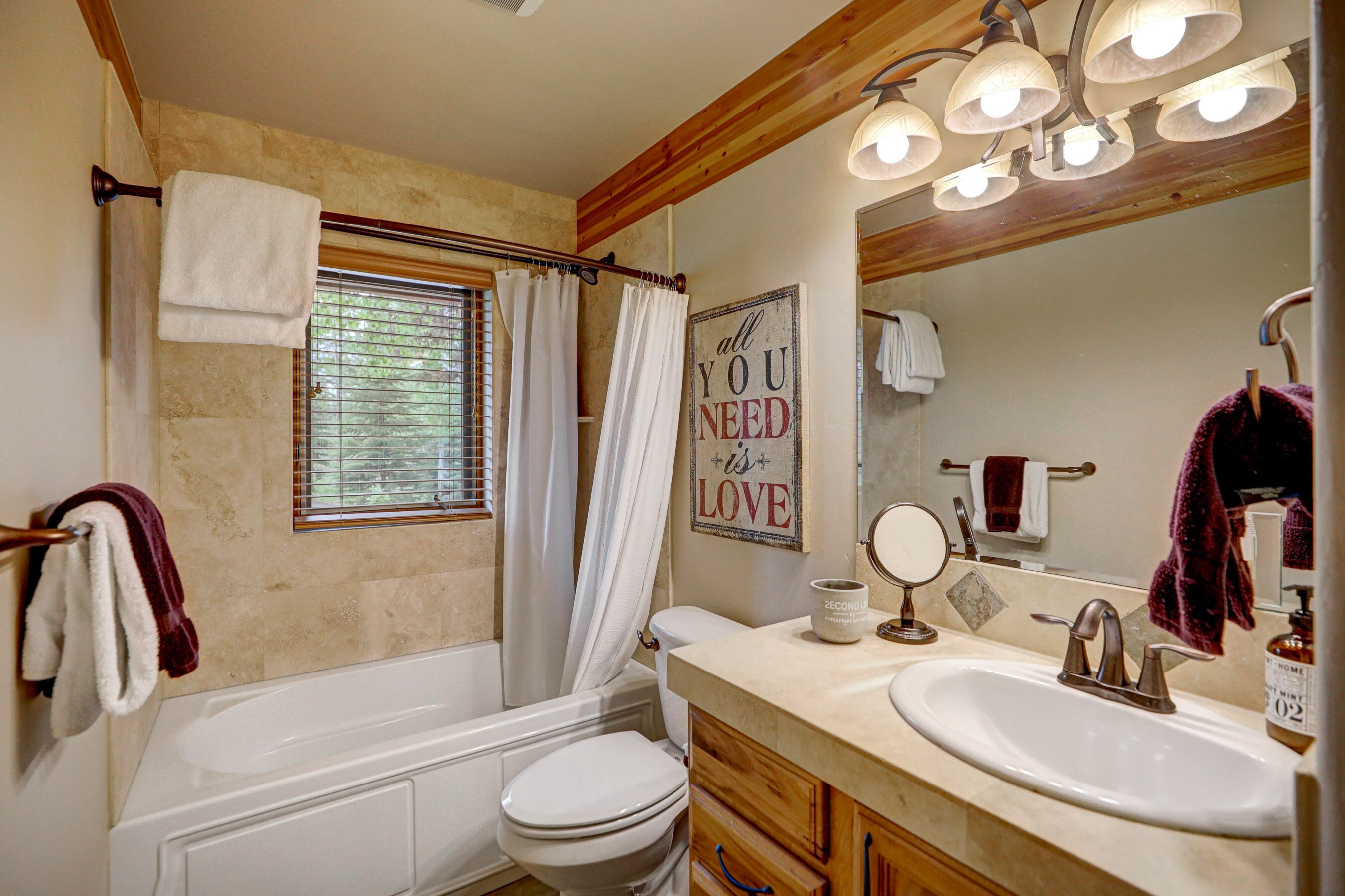 A bathroom with a bathtub, toilet, vanity with a sink, and a mirror.