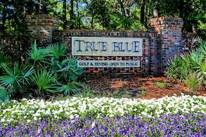 A sign for 'True Blue' with a brick wall and greenery. - Updated condo near golf with pool, hot tub, & tennis access - balcony, W/D, & AC (Pawleys Island)