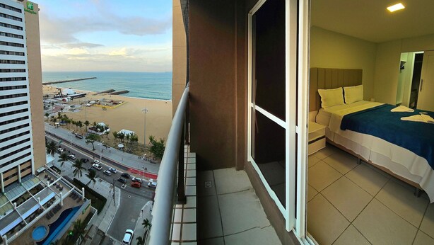 A hotel room with a large balcony overlooking a beach and cityscape. - Terraços do Atlântico By Solemar (Fortaleza)