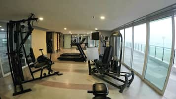 Una palestra con attrezzature per esercizi, un tapis roulant e un'ampia vetrata con vista.