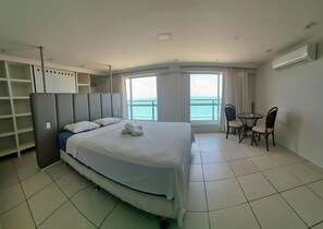 A hotel room with a bed, a desk, and a chair. There is a window with a view of the sea. - Terraços do Atlântico By Solemar (Fortaleza)