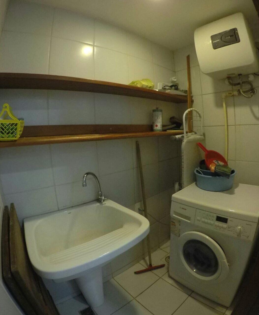 Un baño pequeño con un lavamanos, una lavadora y un estante con artículos de aseo.