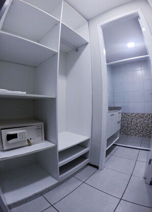 A bathroom with white tiled walls, a shower area, and a microwave on a shelf. - Terraços do Atlântico By Solemar (Fortaleza)