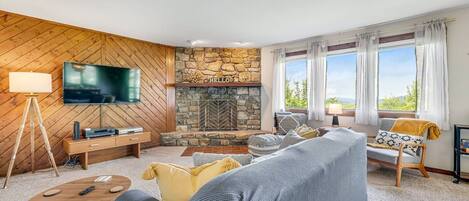 A cozy living room with a stone fireplace, a television, and comfortable seating.