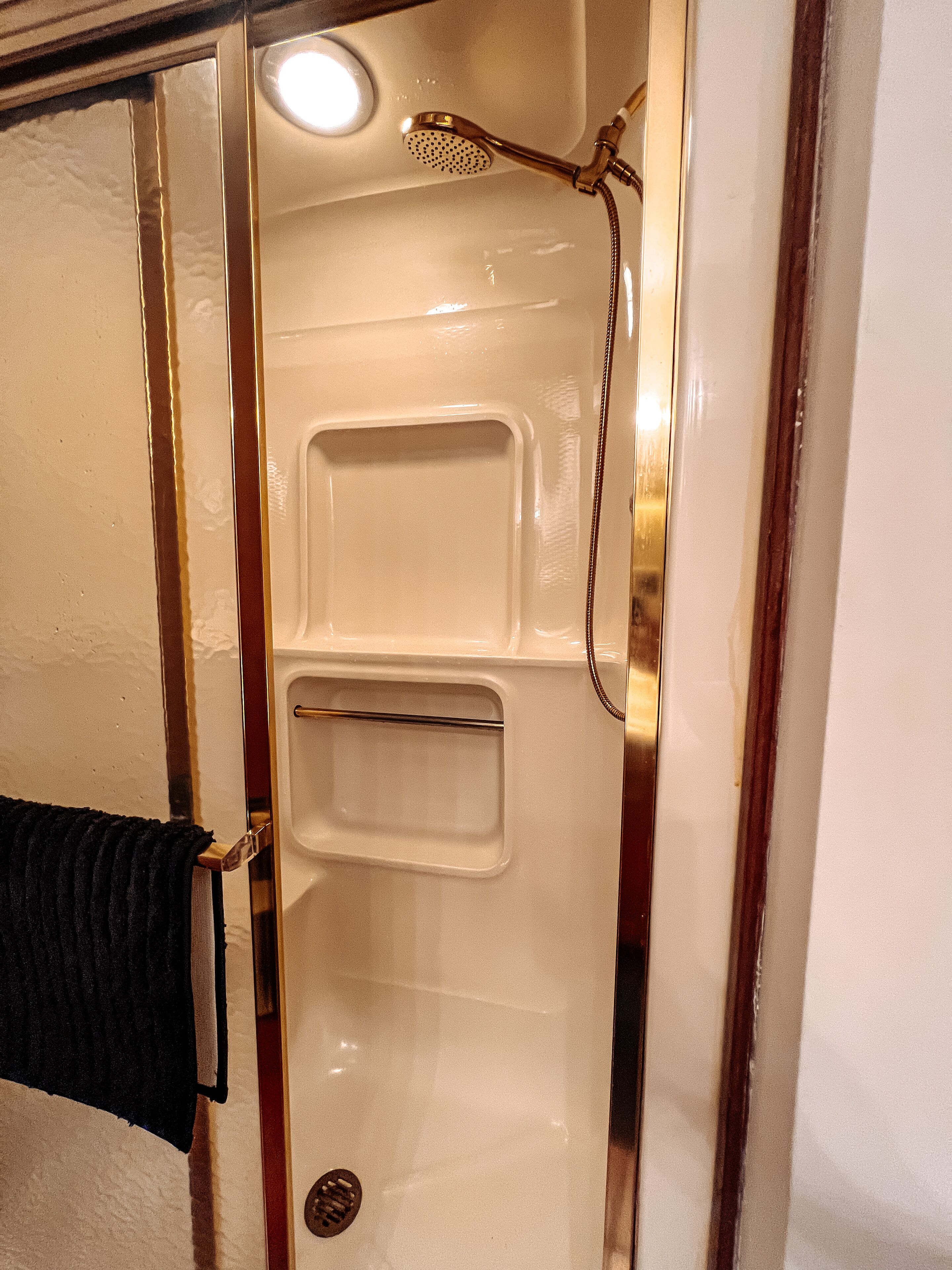 Een badkamer met een douche, een handdoekhouder en een wastafel.