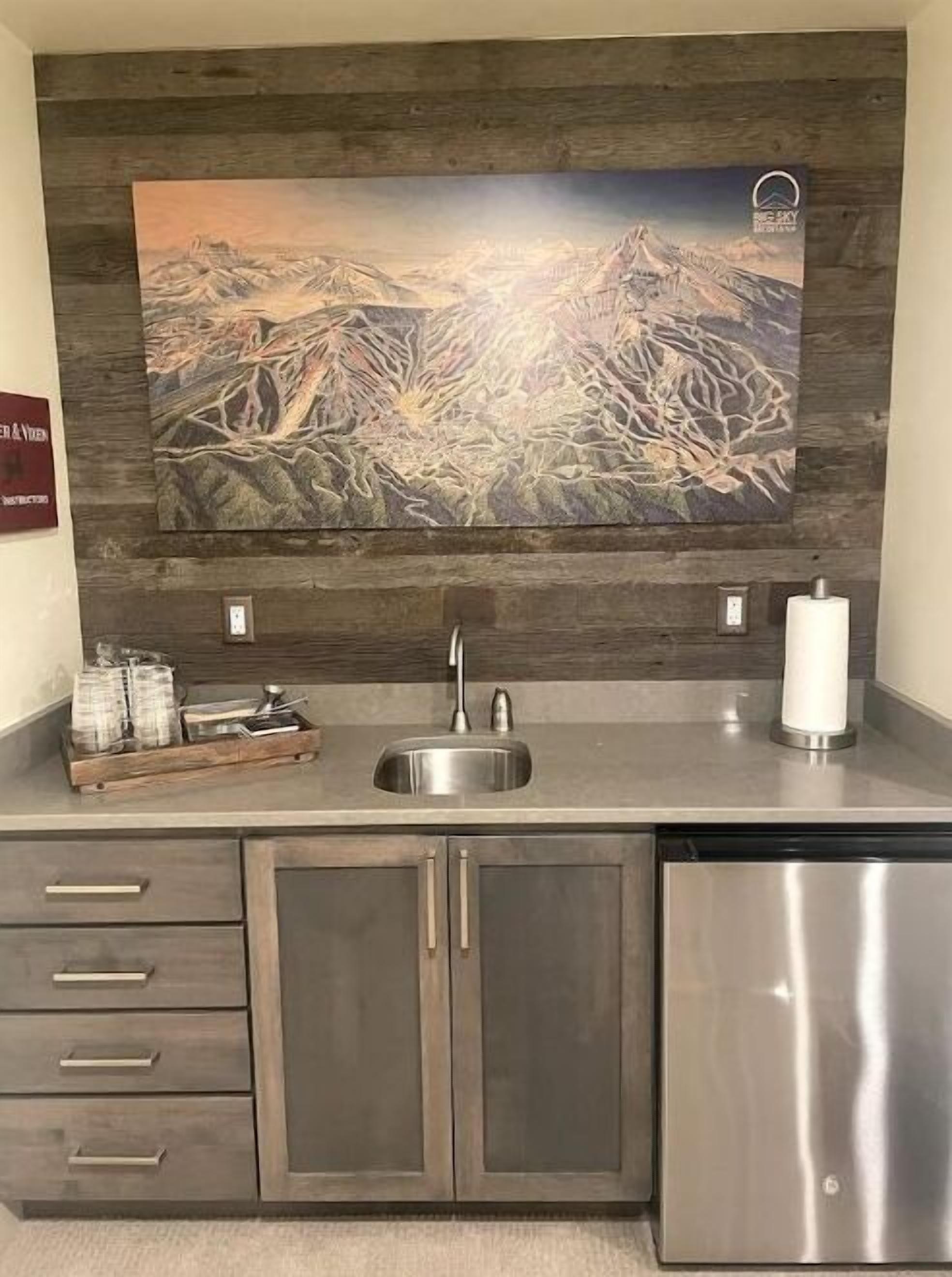 A kitchen with a wooden backsplash, a stainless steel sink, and a dishwasher.