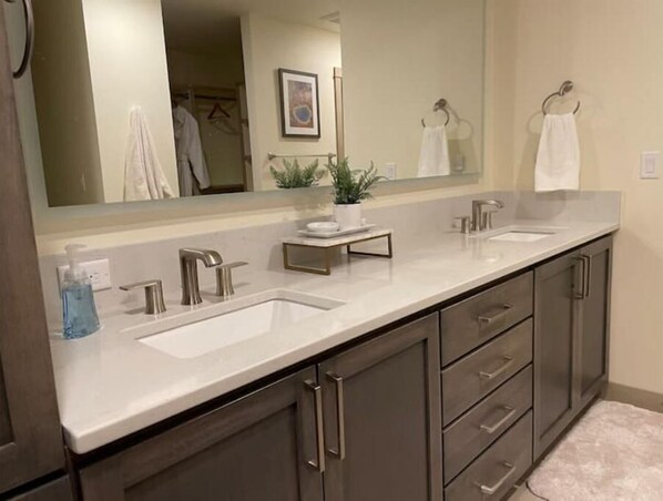 A bathroom with a double sink vanity, a large mirror, and a towel rack.