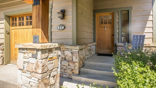 A wooden house with a stone foundation, a wooden front door, and a mailbox. - Contemporary townhome in the heart of Town center (Big Sky)