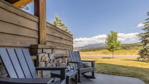 A wooden cabin with two Adirondack chairs on a patio, overlooking a mountainous landscape. - Contemporary townhome in the heart of Town center (Big Sky)