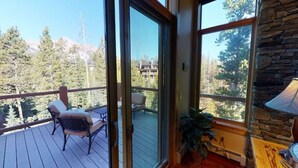 Un balcone con vista su alberi e montagne, un muro in pietra e un tavolo con una lampada.