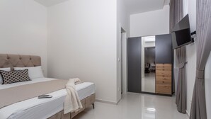 A bedroom with a bed, a TV mounted on the wall, and a wardrobe.