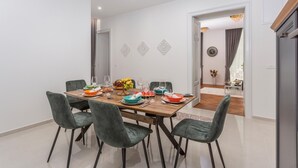 A dining area with a wooden table set for six, surrounded by green upholstered chairs.